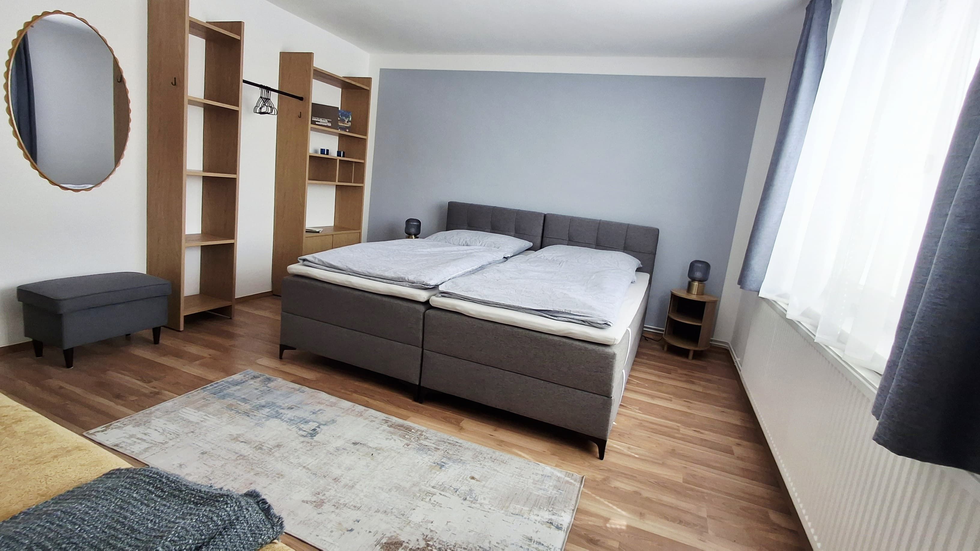 Modern guest room with double bed, gray curtains and wooden furniture.