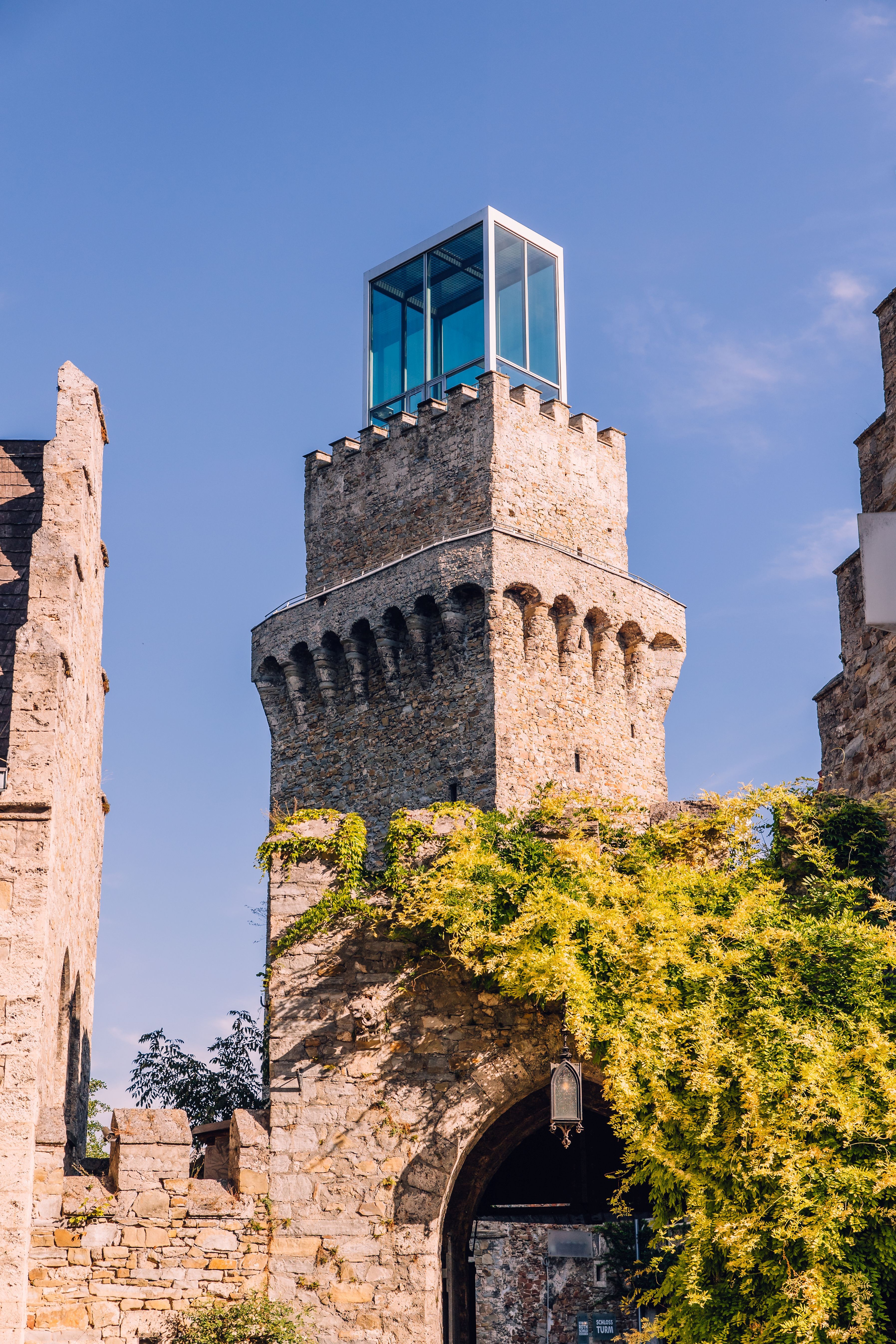 The historic castle tower of Schloss Rothschild in Waidhofen an der Ybbs, featuring a modern glass structure and a green archway.
