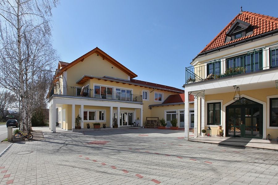 Exterior view of a yellow vineyard with red roofs and a paved courtyard.