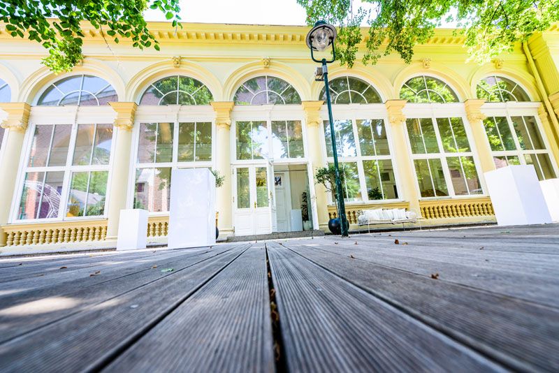 Exterior view of the Kursalon Mödling with large windows and wooden floor.