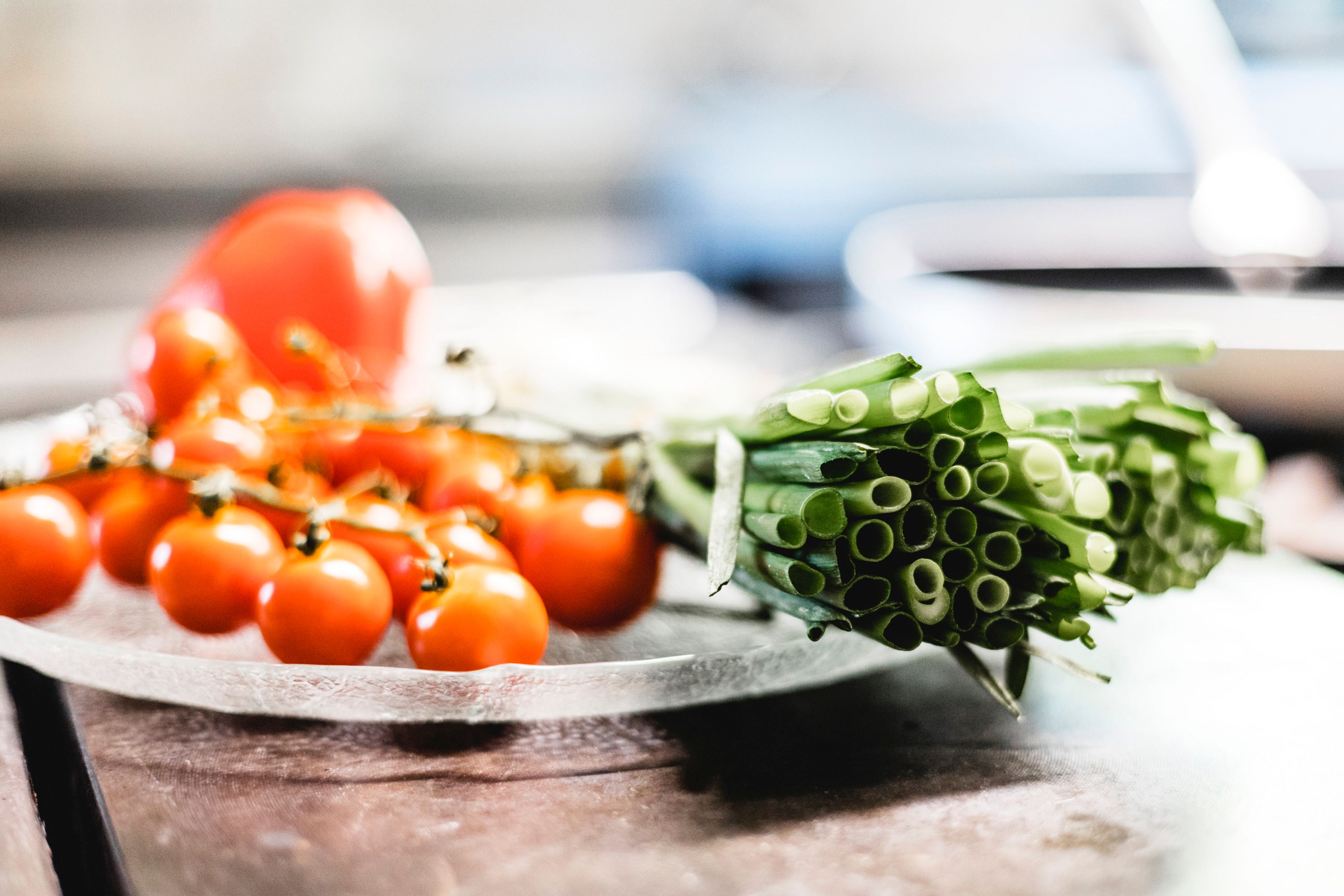 Close-up of fresh cherry tomatoes and spring onions on a plate.