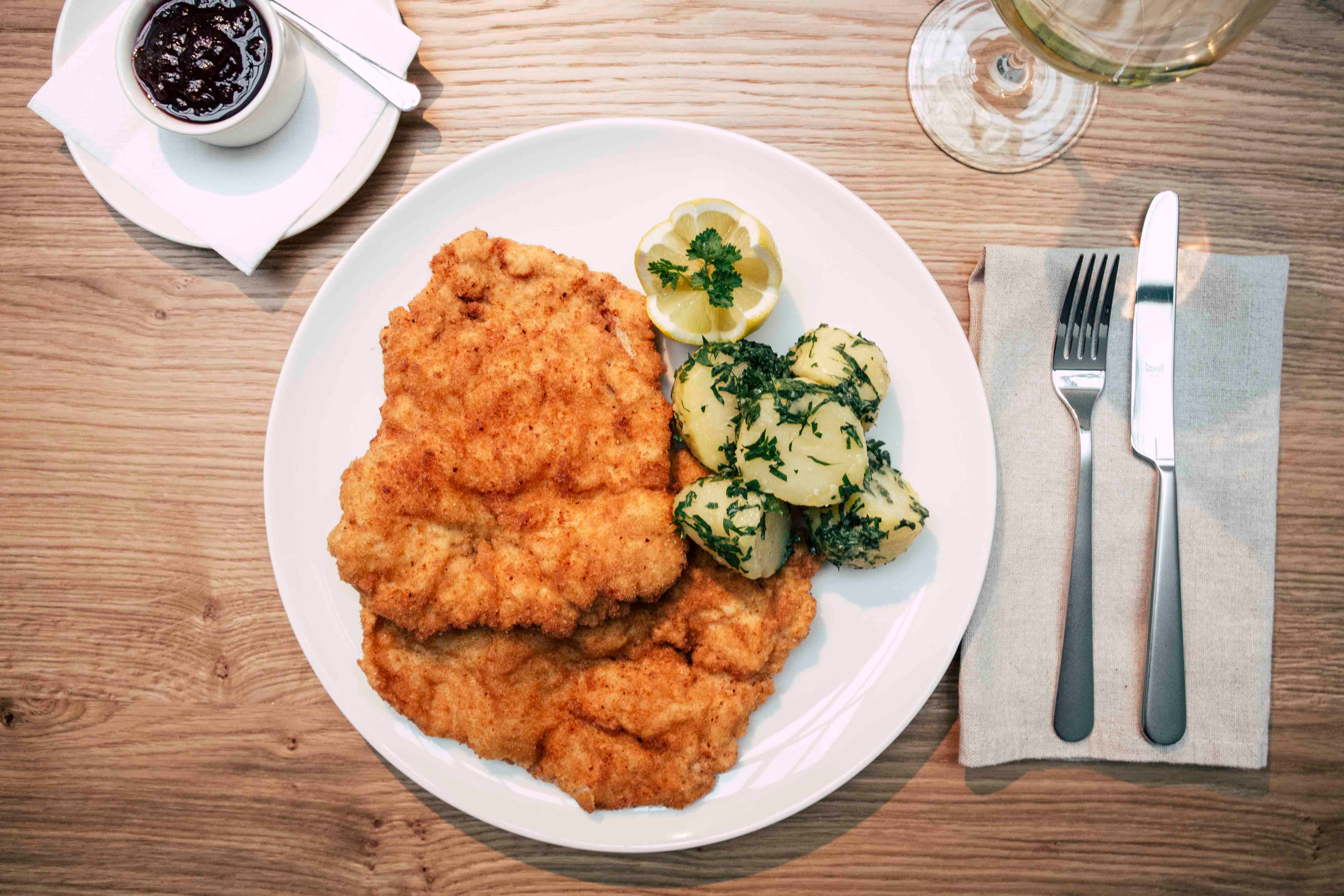 Wiener schnitzel with parsley potatoes and cranberries.