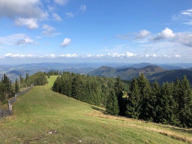 View of a green mountain landscape with forests and blue sky.