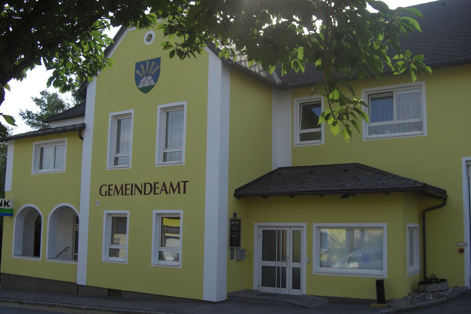 Yellow building with the inscription 'GEMEINDEAMT' and a coat of arms above it.