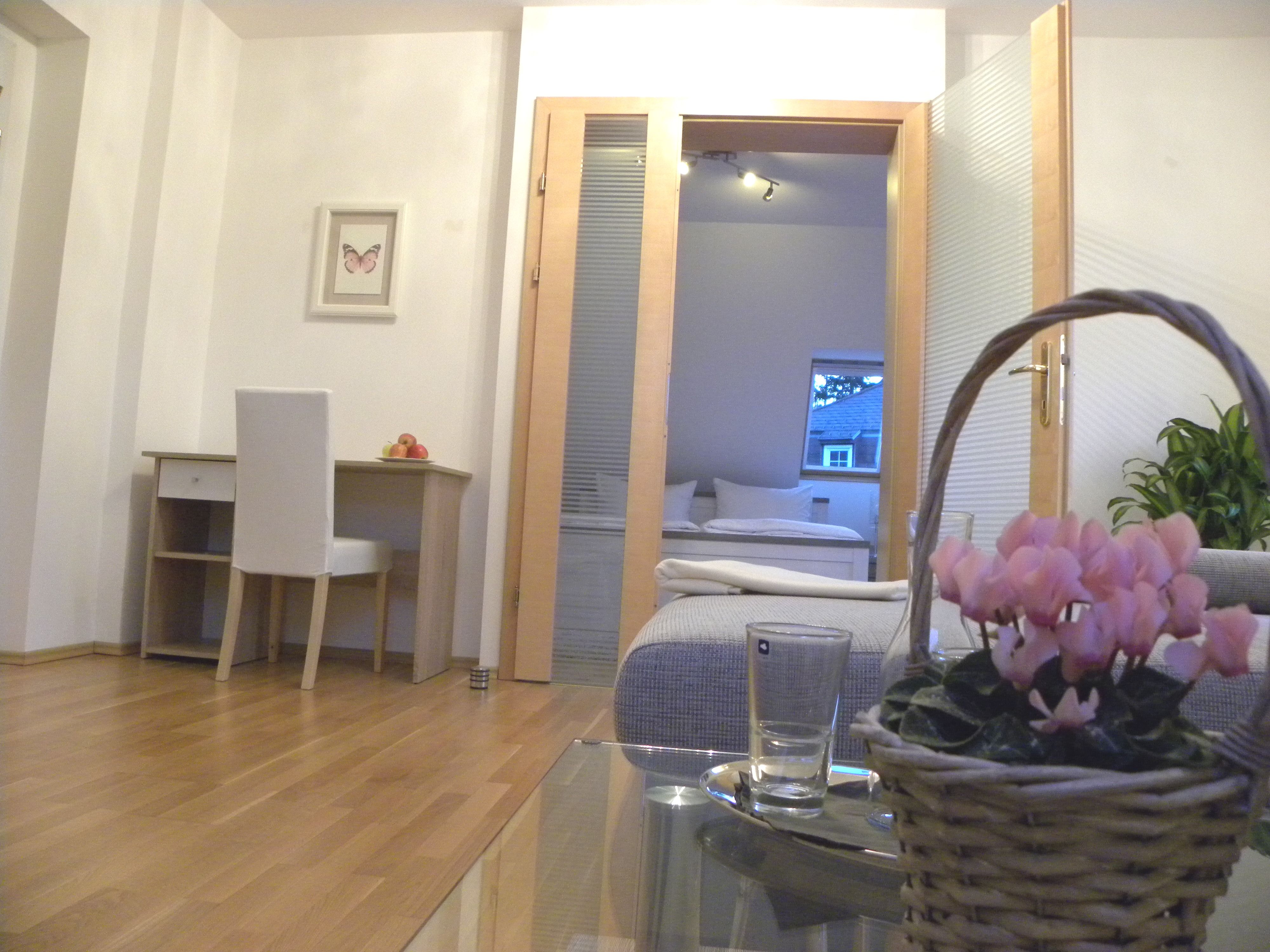 Interior with desk, chair, flowers in a basket and view into the bedroom.