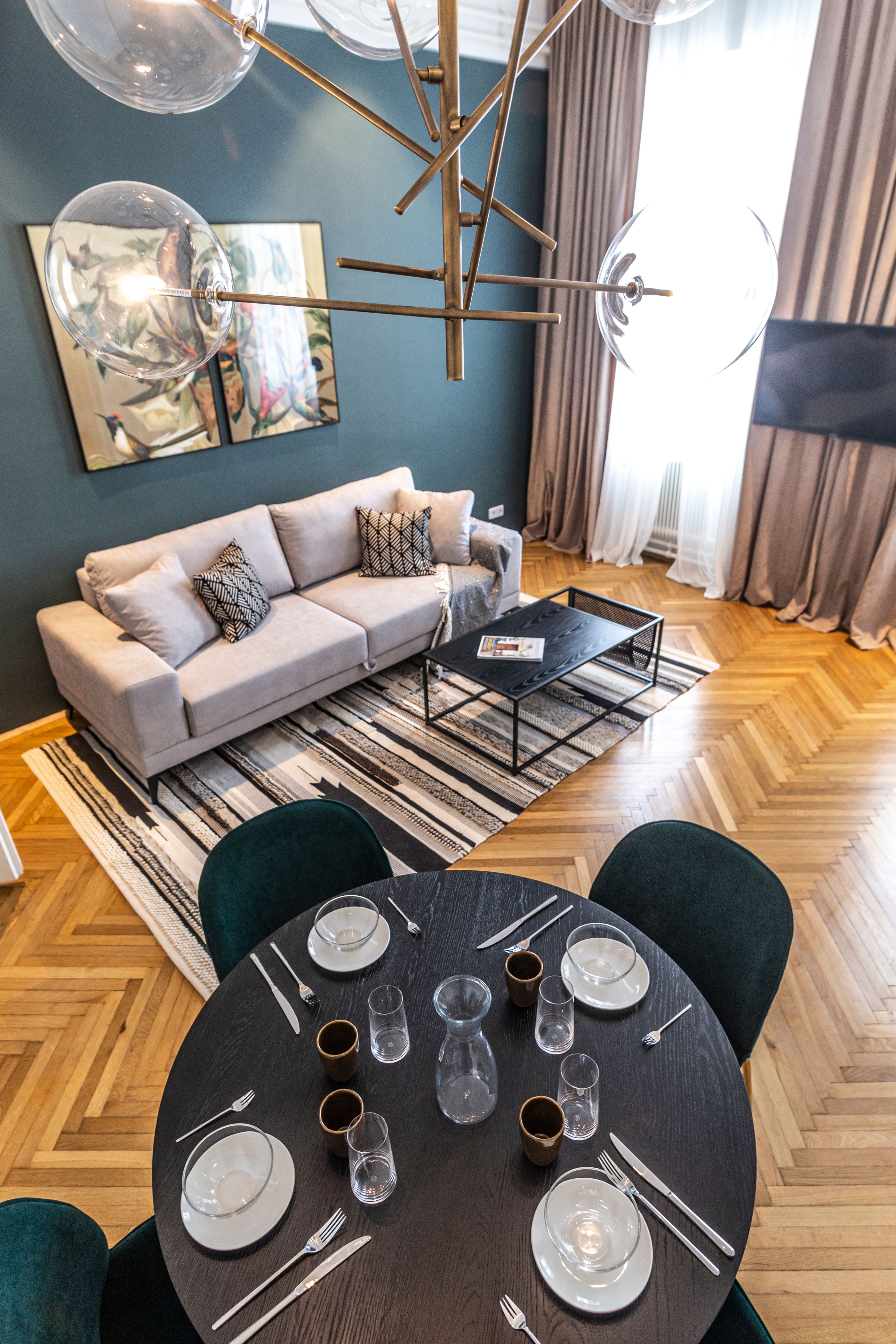 Modern living room with sofa, coffee table, carpet and dining table with place settings.