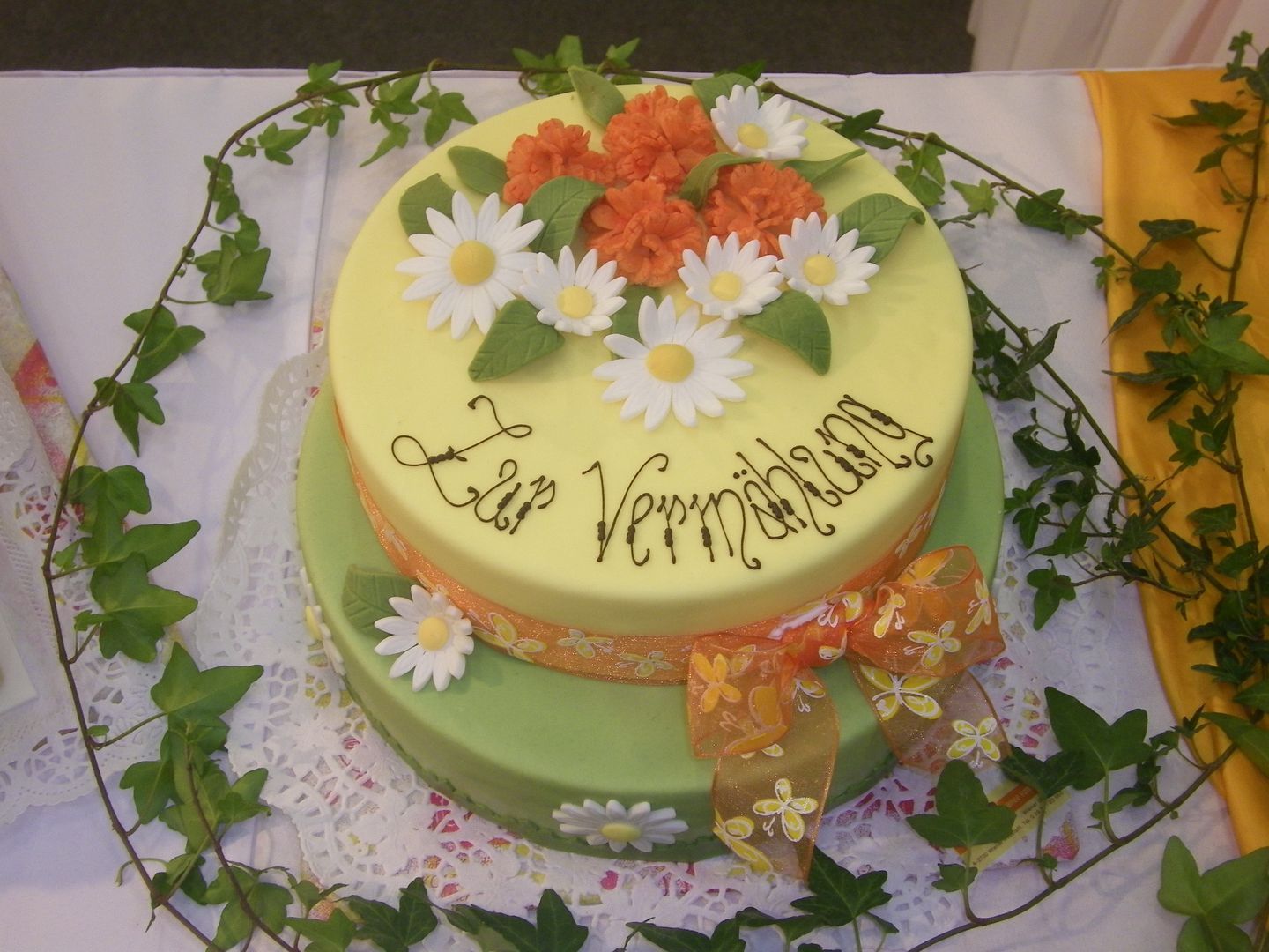 Two-tier cake with flowers and 'Zur Vermählung' lettering.