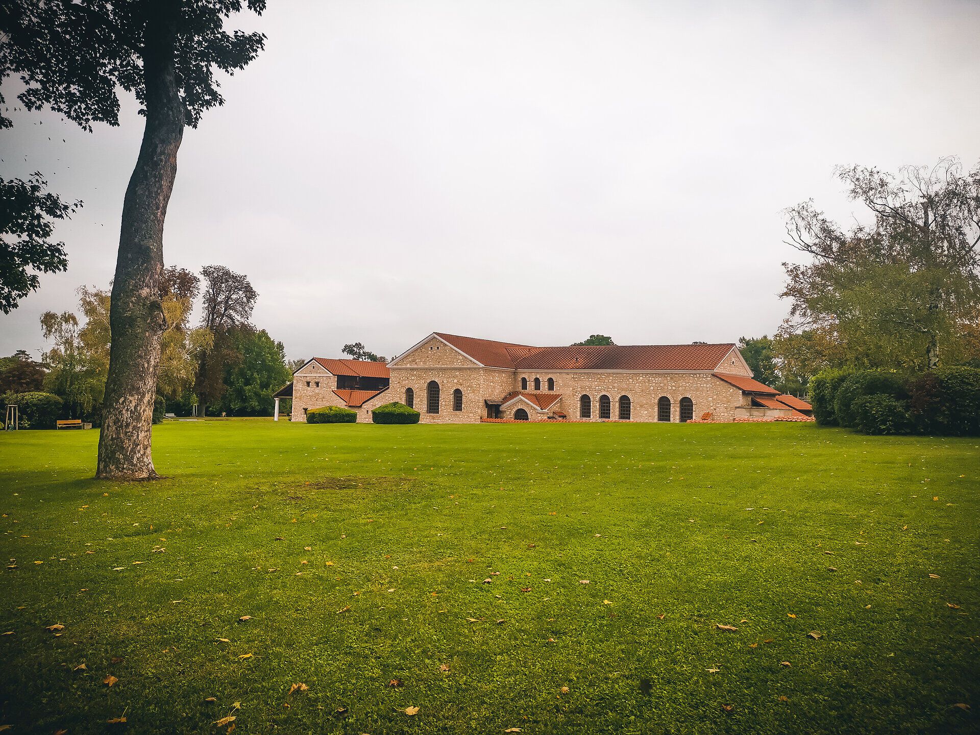 A picturesque backdrop unfolds in the gentle autumn landscape, where the rolling hills and green grass blend harmoniously together. The historic architecture radiates peace and serenity, while the trees rustle in the gentle wind and the colors of autumn come to life.