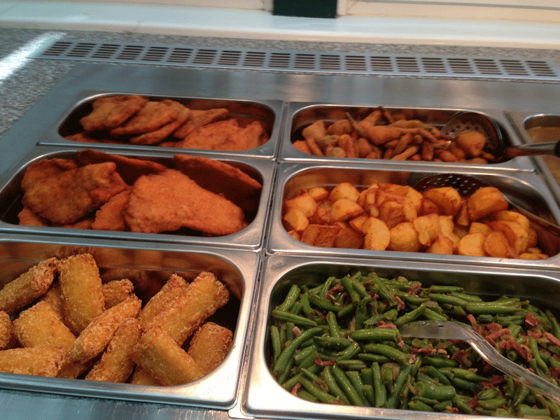 Buffet with breaded dishes, potatoes and green beans.