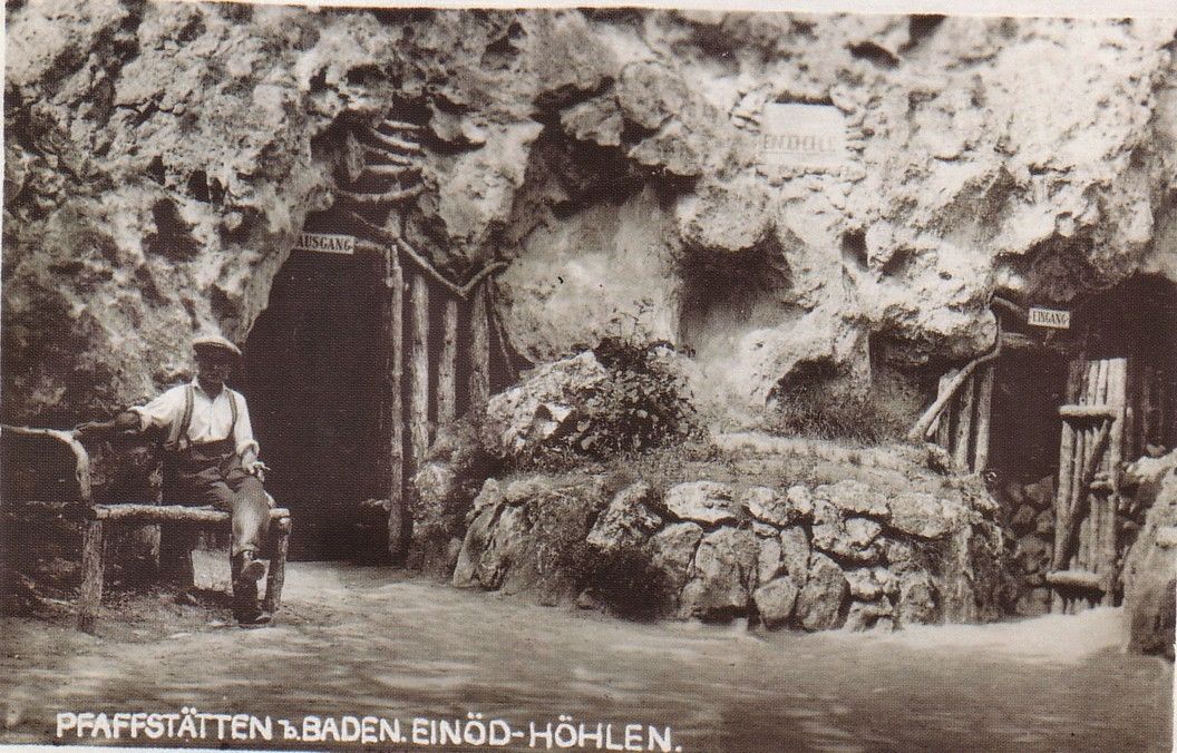 Historical photo of the Einödhöhle cave in Pfaffstätten, Baden, with a man on a bench in front of the cave entrance.