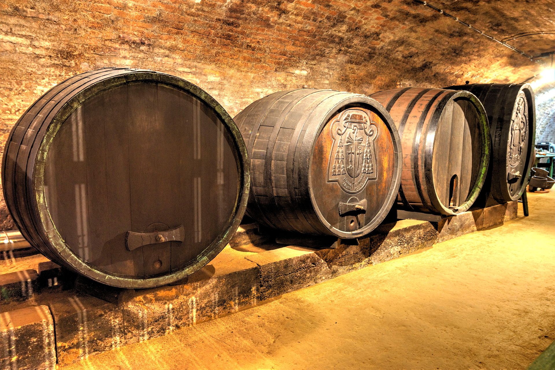 Wine barrels in a wine cellar with a brick ceiling.
