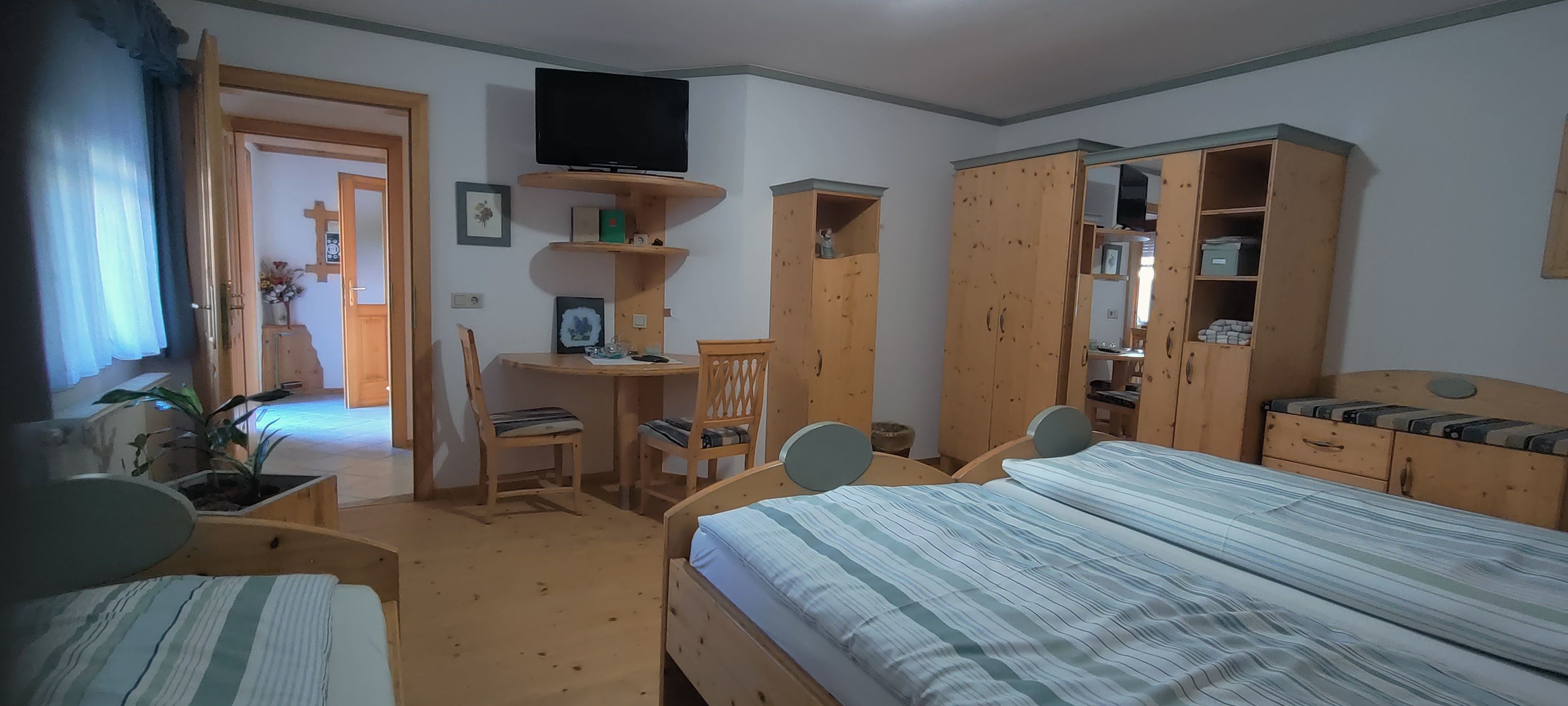 Comfortable bedroom with wooden furniture, double bed, desk and TV.
