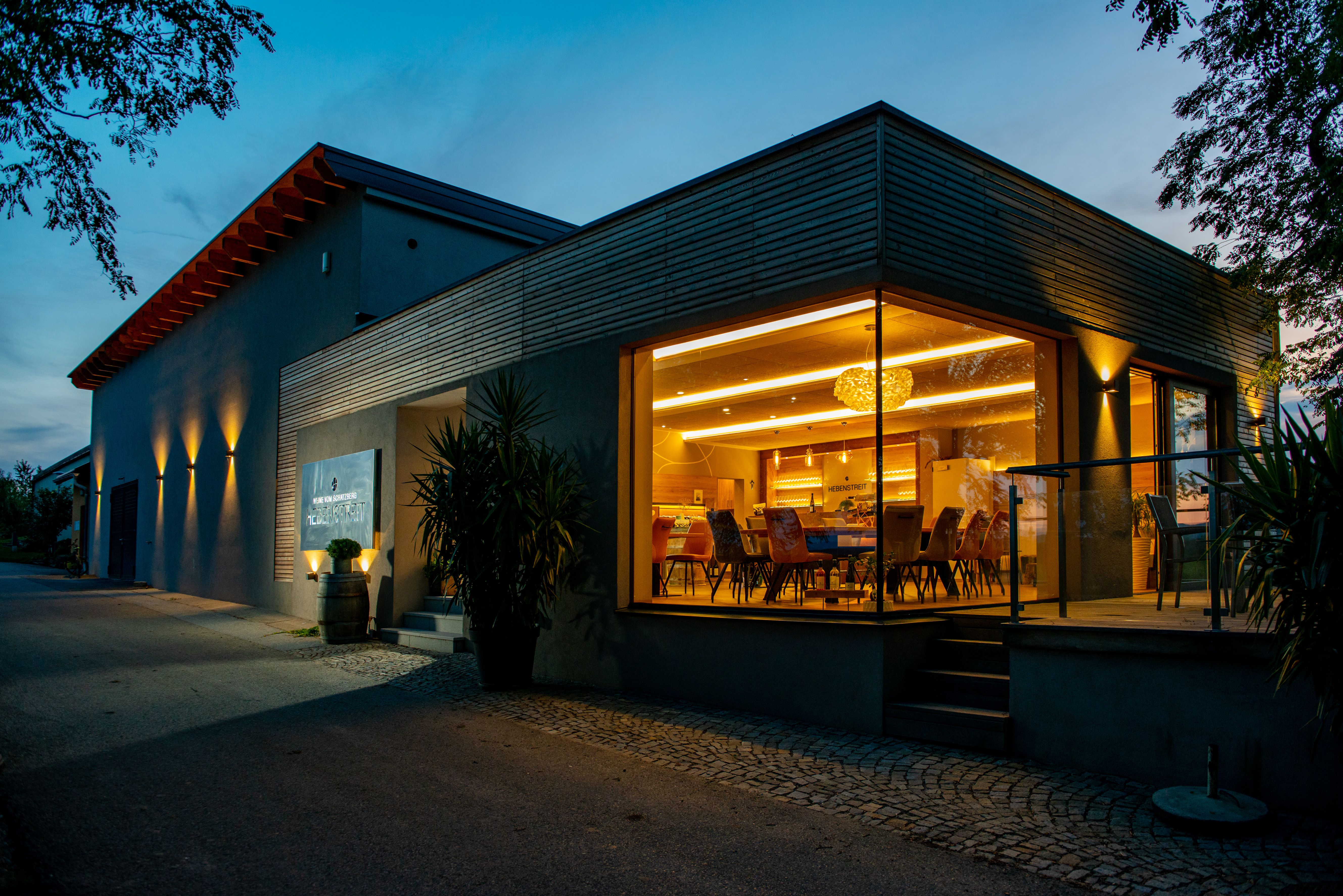 Modern building with glass front and interior lighting at dusk.