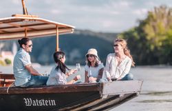 Eine Holzzille mit Menschen fährt auf der Donau in der Wachau.