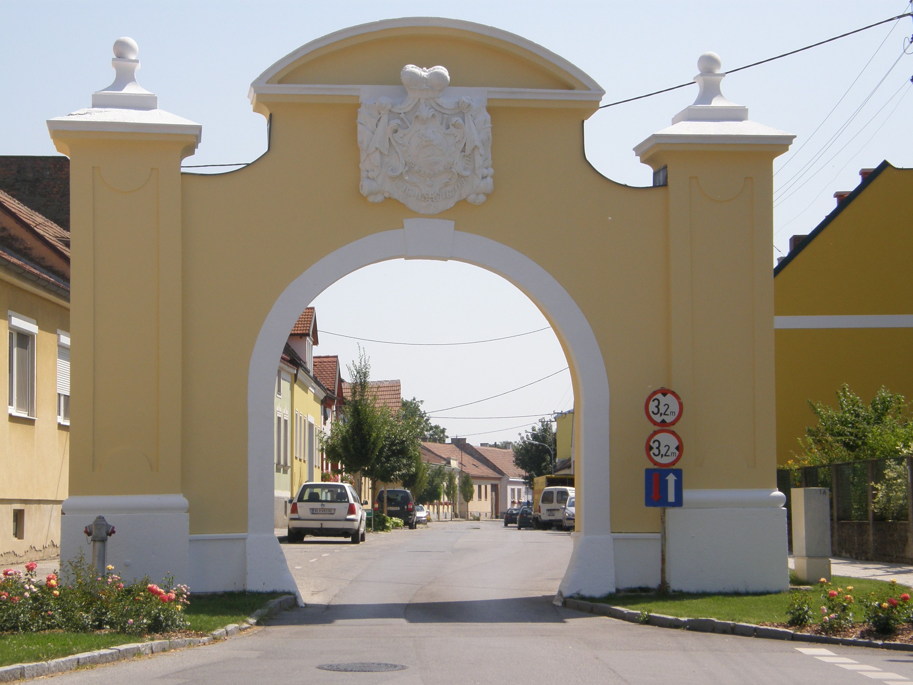 Yellow gate with coat of arms spanning a street.