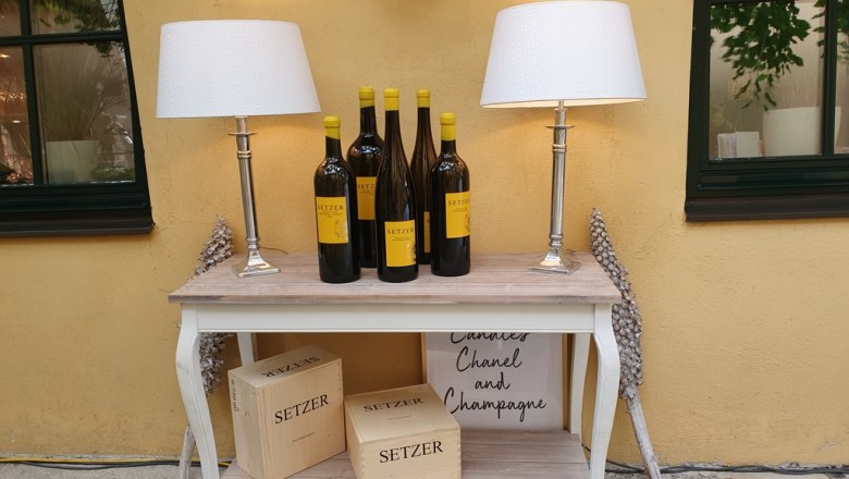 Console table with wine bottles, lamps and wooden boxes.