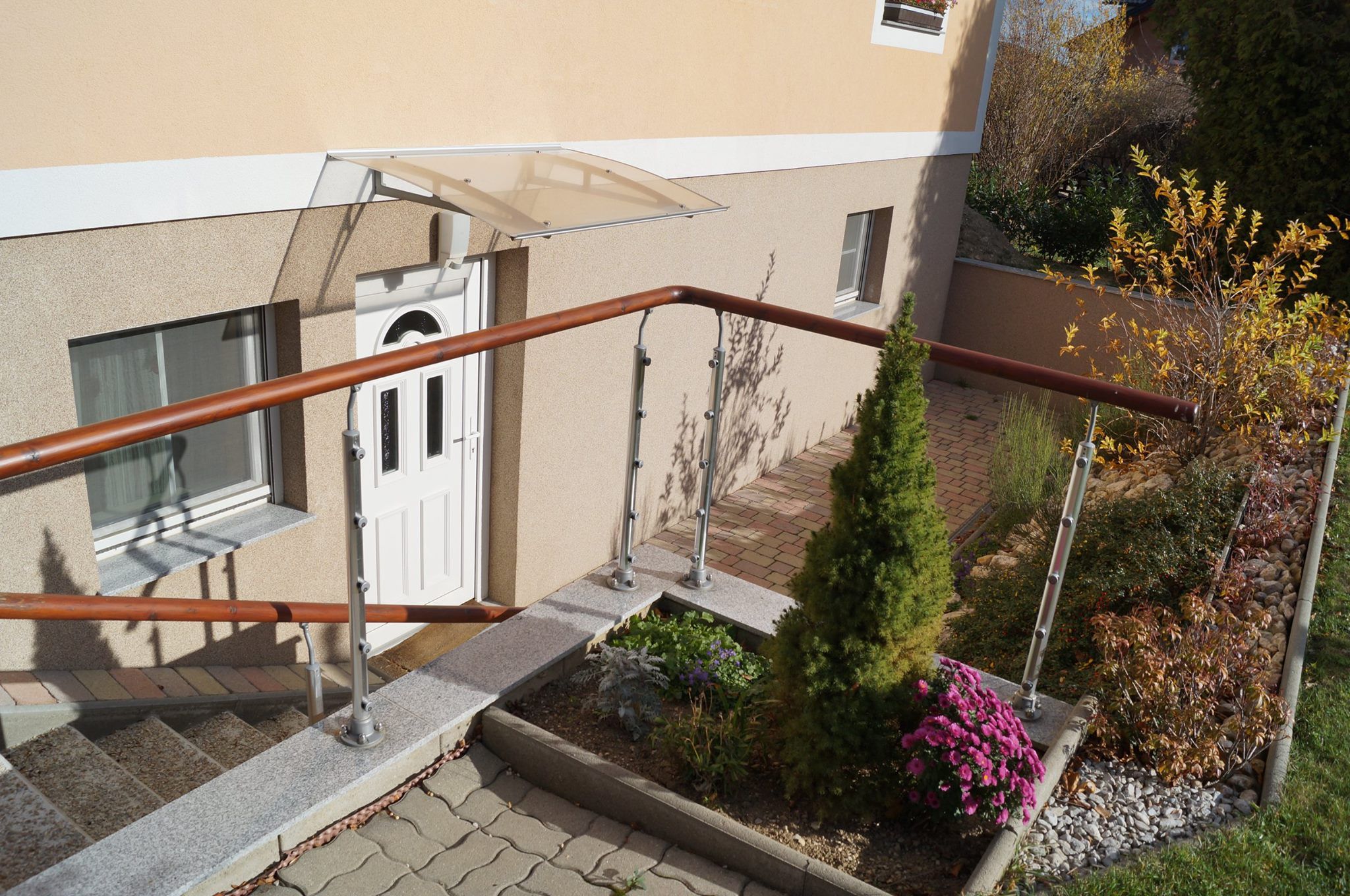 Entrance area of a house with white door, railing and garden.