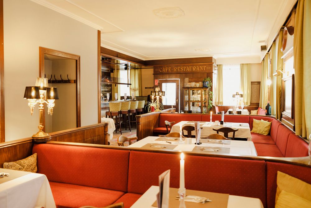Cozy café-restaurant with red benches and elegant lighting.
