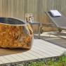 Stone bathtub and sun loungers on the outdoor wooden terrace.