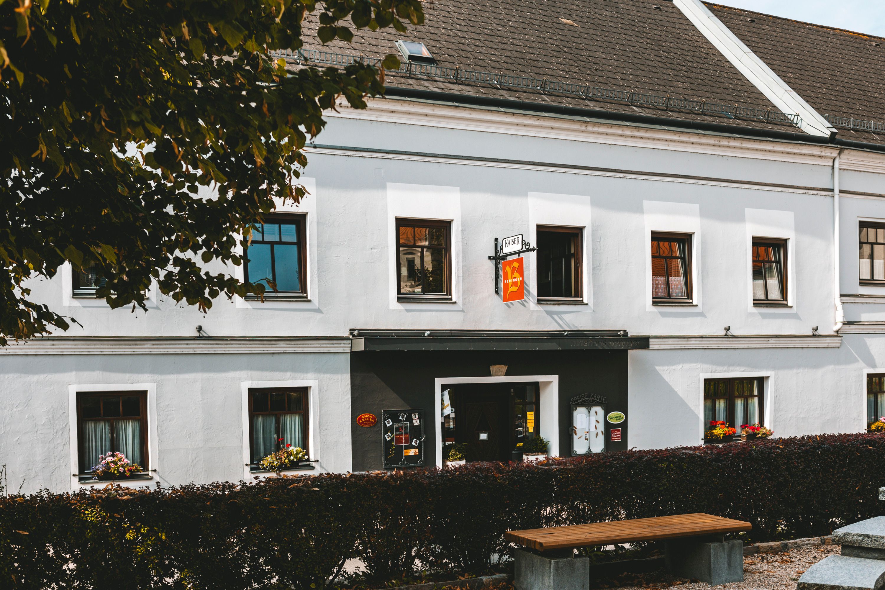 A traditional inn in Mank with white walls and flower boxes on the windows.