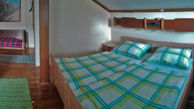 A cozy room with double bed, sofa, table and window.