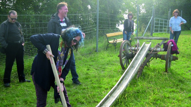 Person plays farmer's golf with a wooden club on a meadow.