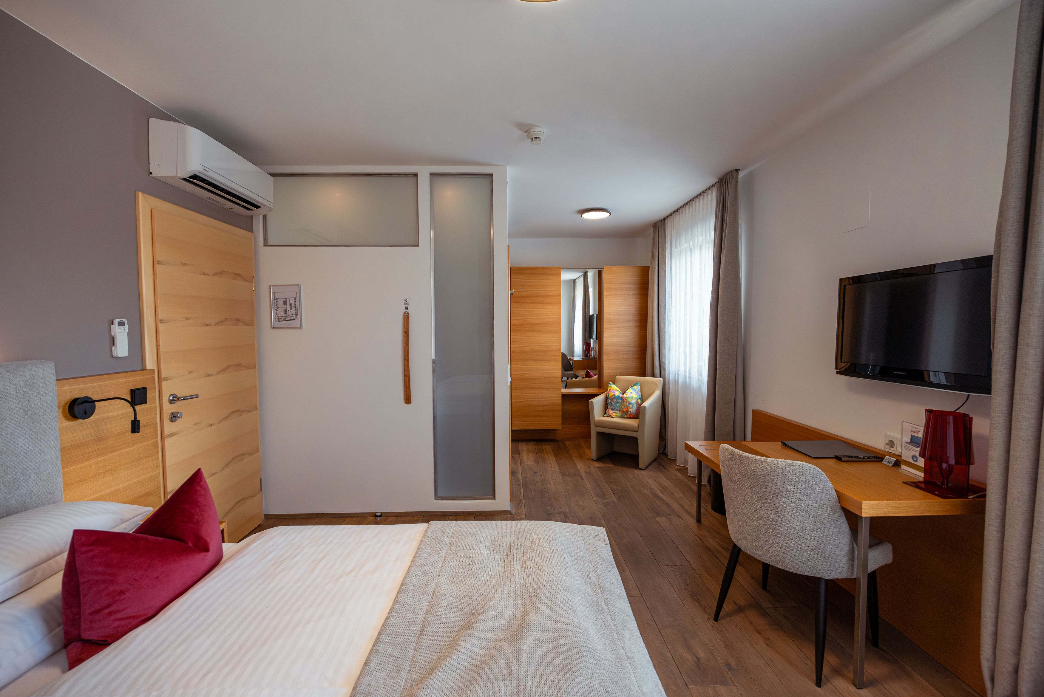 Modernly furnished hotel room with bed, desk, chair and TV.