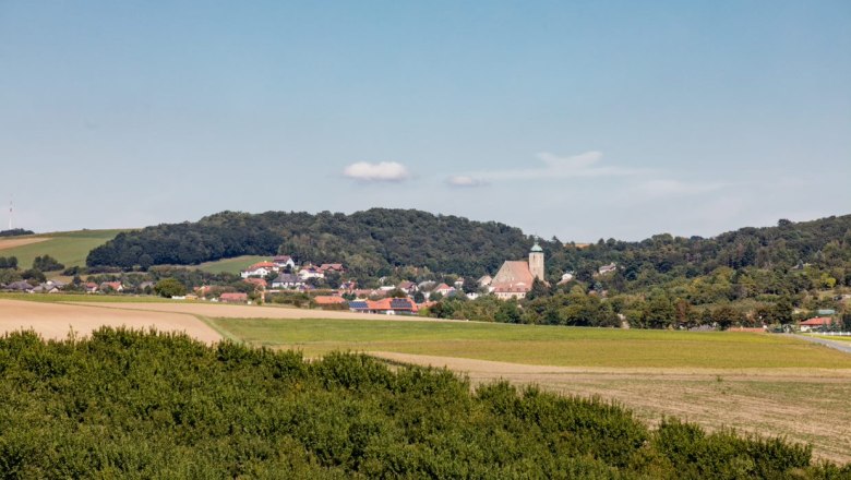 Landscape view of Gro&szlig;ru&szlig;bach with church and hills in the background.