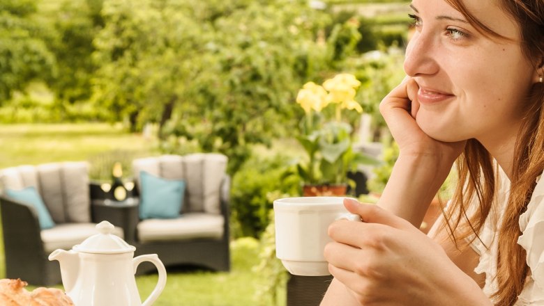 Woman enjoying coffee outdoors with a view of vineyards.