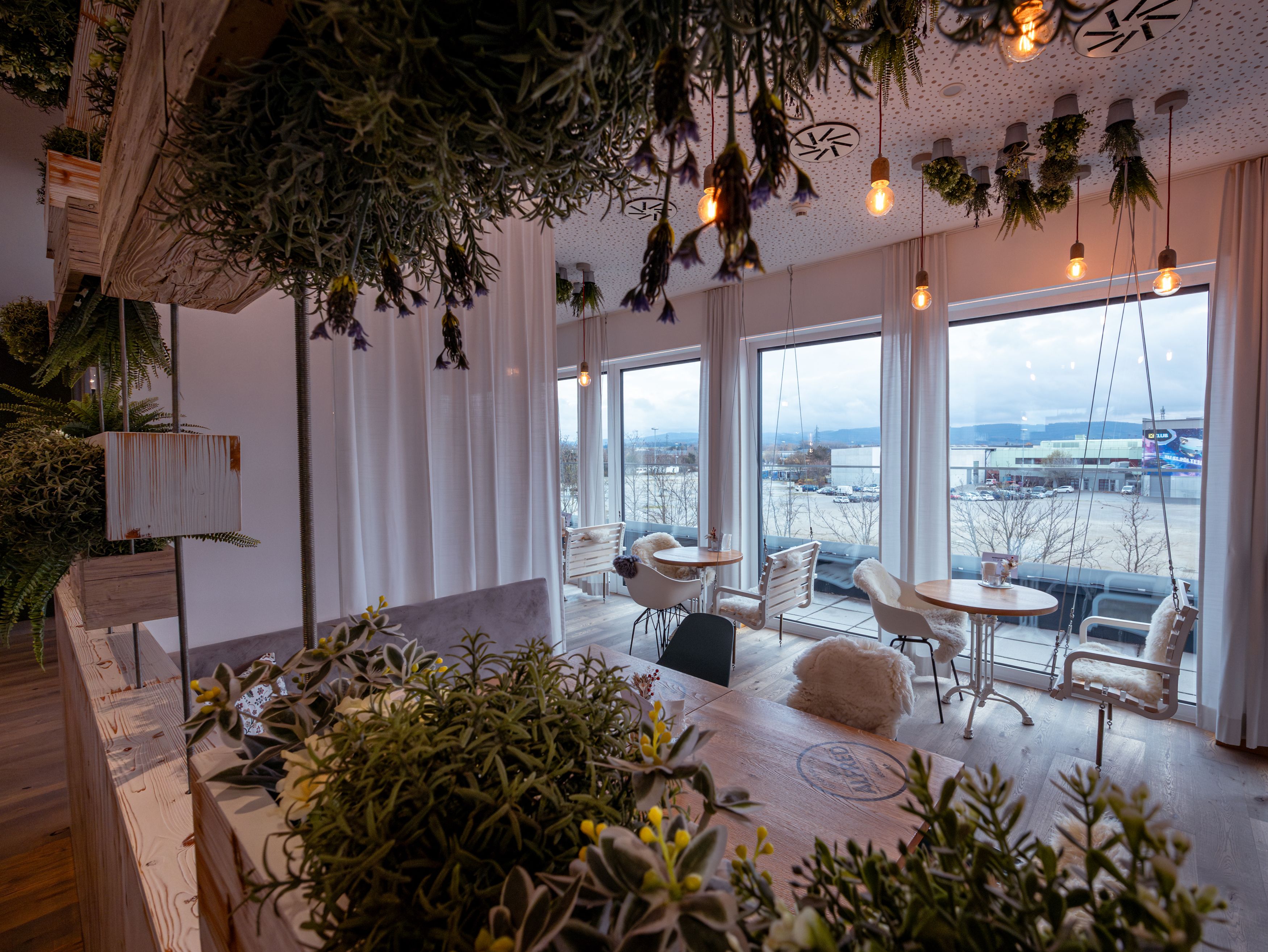 Interior of a café with plants and large windows.
