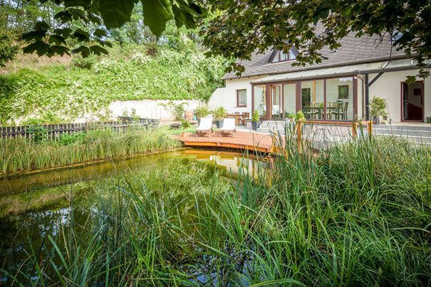 A house with a terrace and swimming pool in the garden, surrounded by lush vegetation.