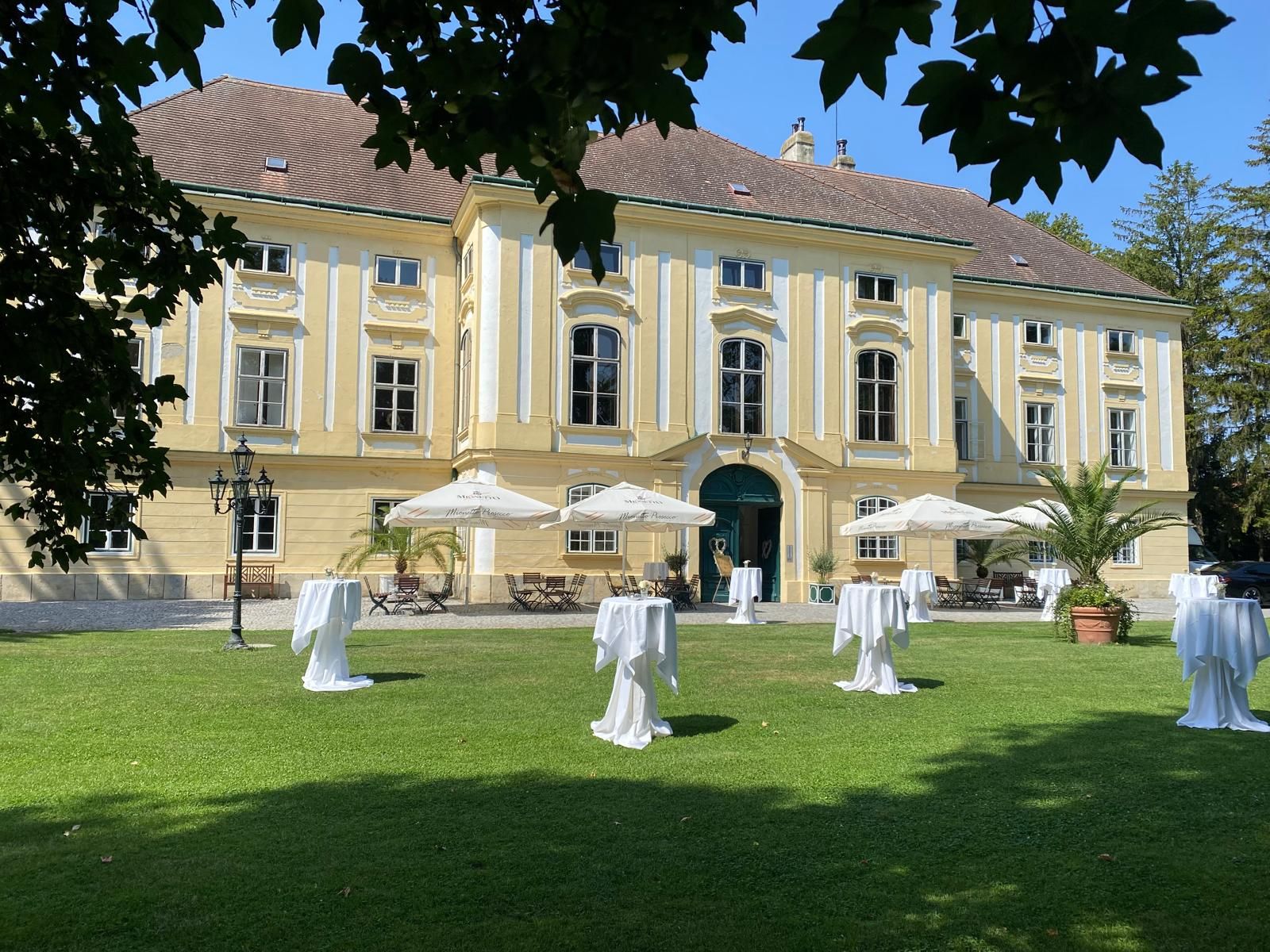 Exterior view of the castle, in the foreground a meadow with white bar tables and white parasols