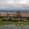 View over the town of Krems with houses, hills and a cloudy sky in the background.