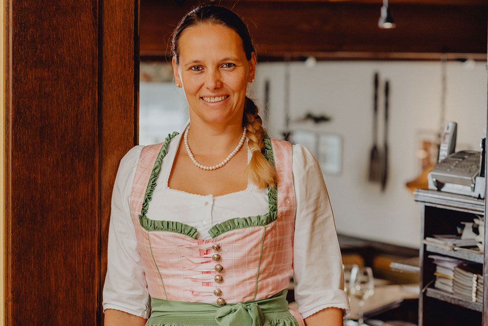 Woman in traditional costume smiling in a restaurant.