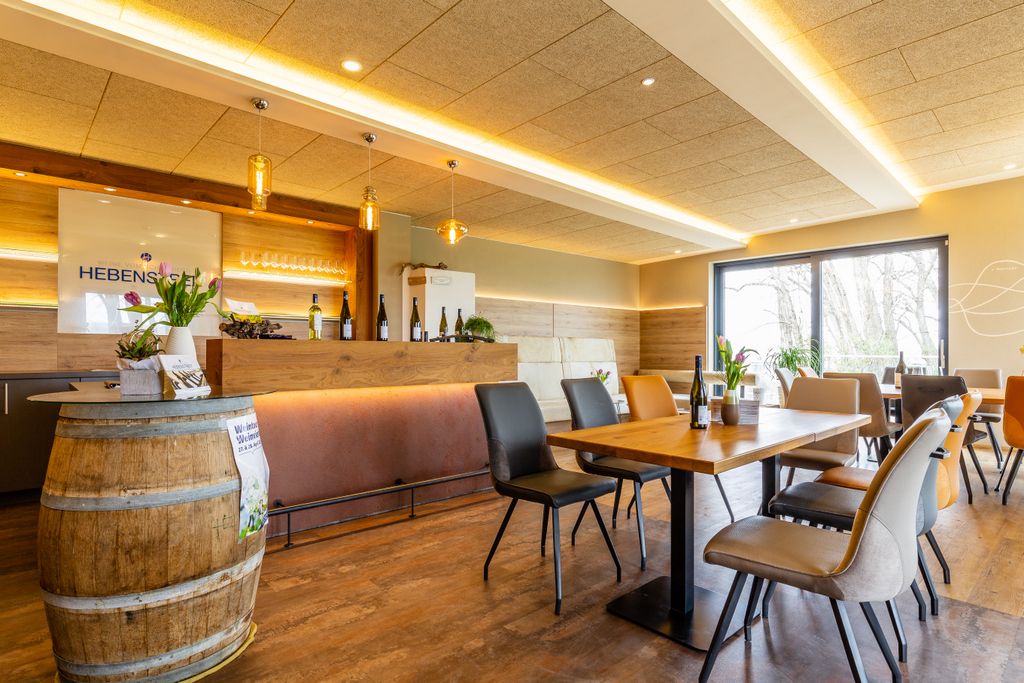 Modern tasting room with wooden tables, chairs and a bar. Wine bottles and flowers decorate the room.