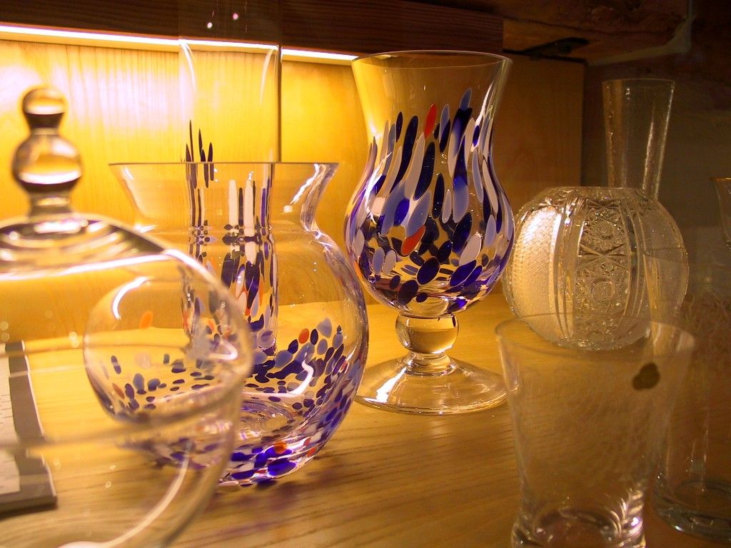 Various colorful glass vases on a wooden shelf.