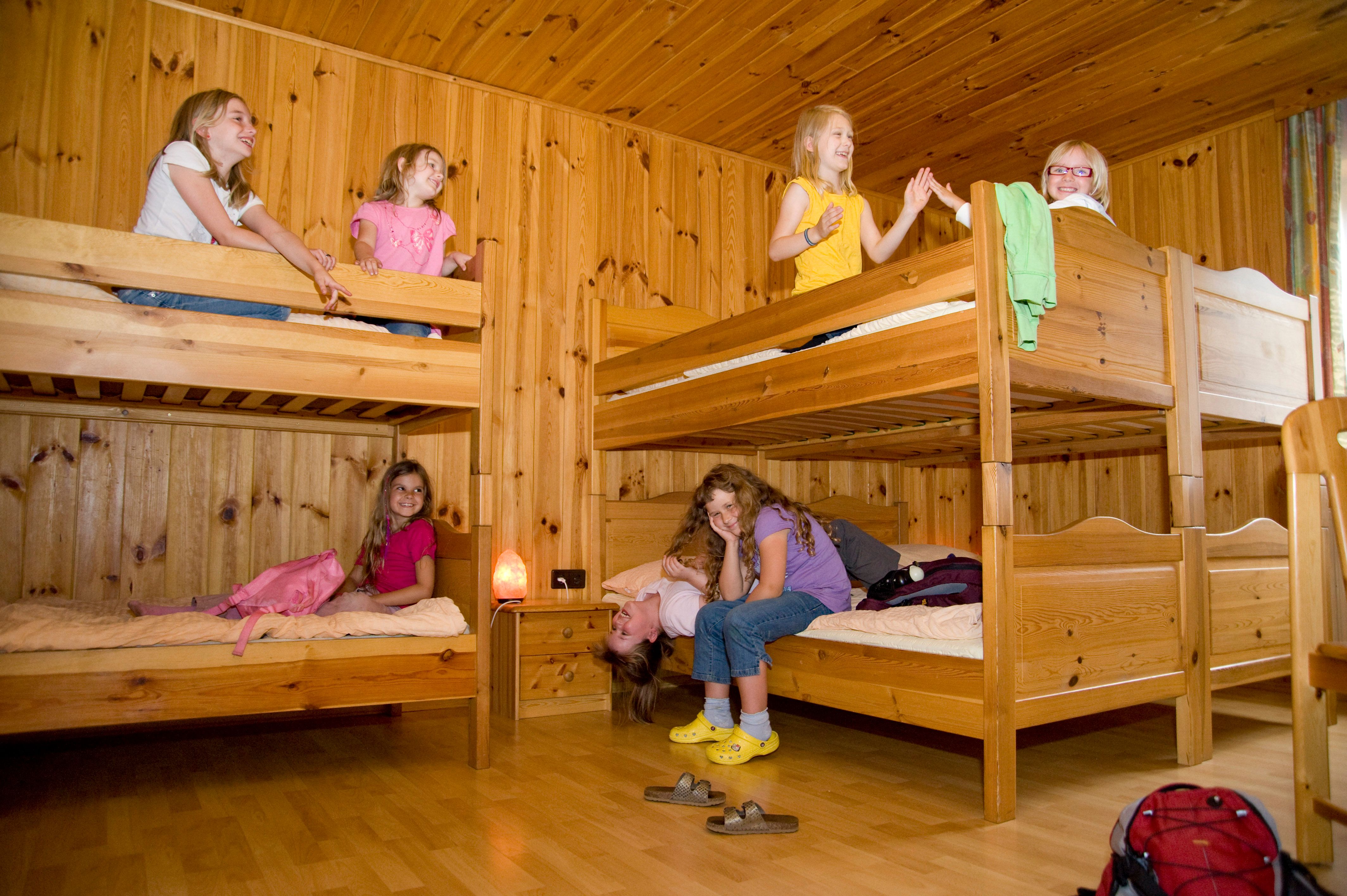 Children play in a room with wooden bunk beds.