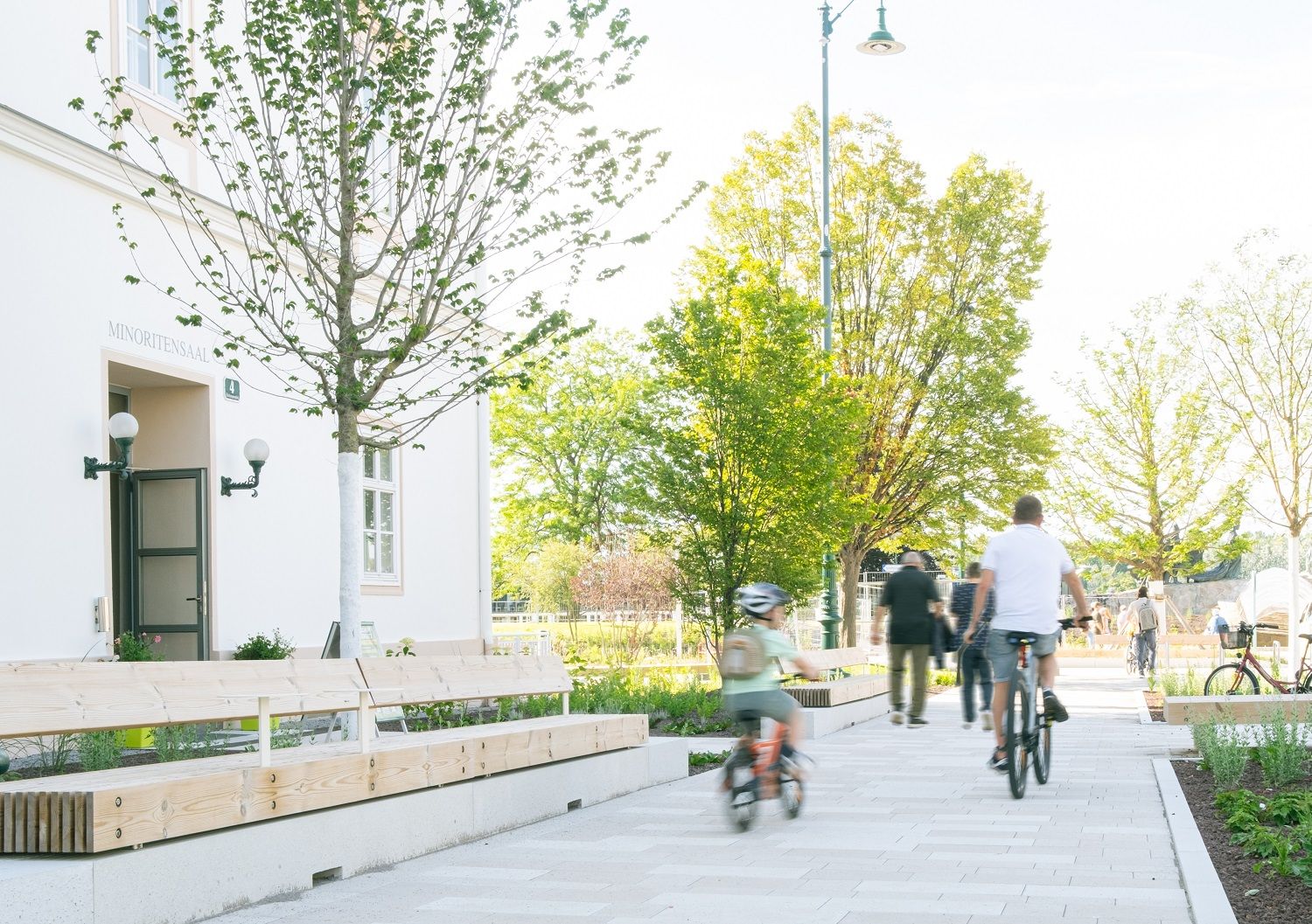 People walking on WEg at Nibelungenplatz with green trees 