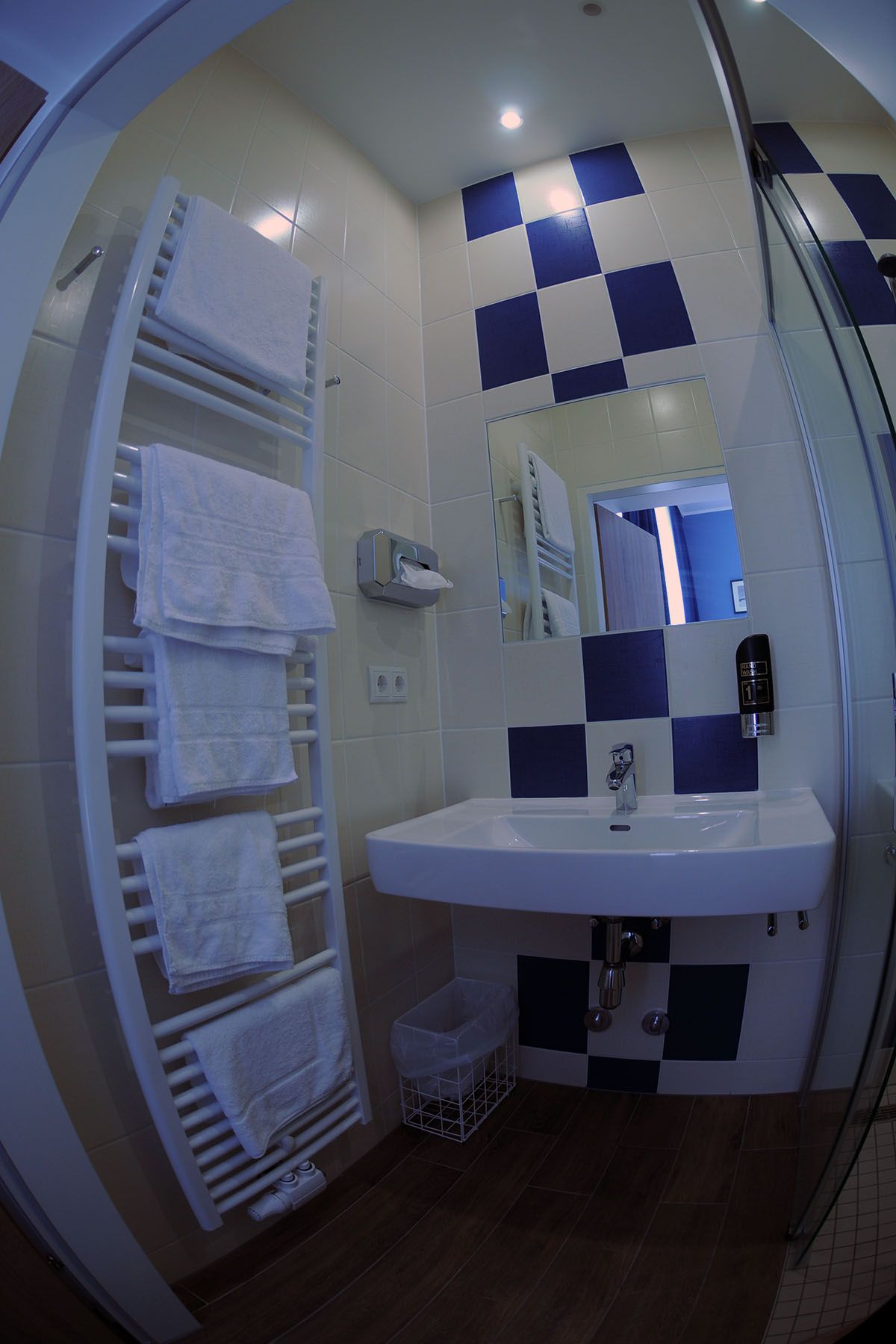 Modern bathroom with blue and white tiles, washbasin, towel rail and mirror.