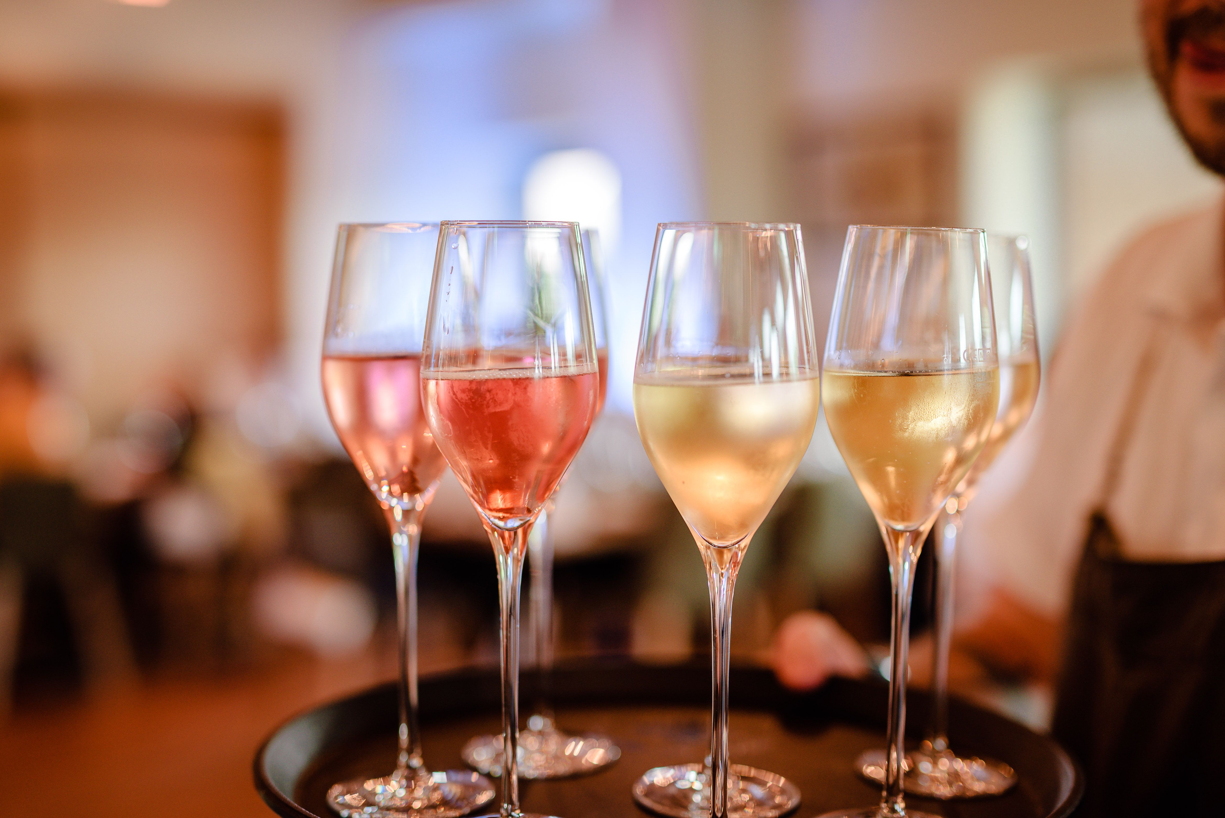 Close-up of champagne glasses on a tray, filled with rosé and white sparkling wine.