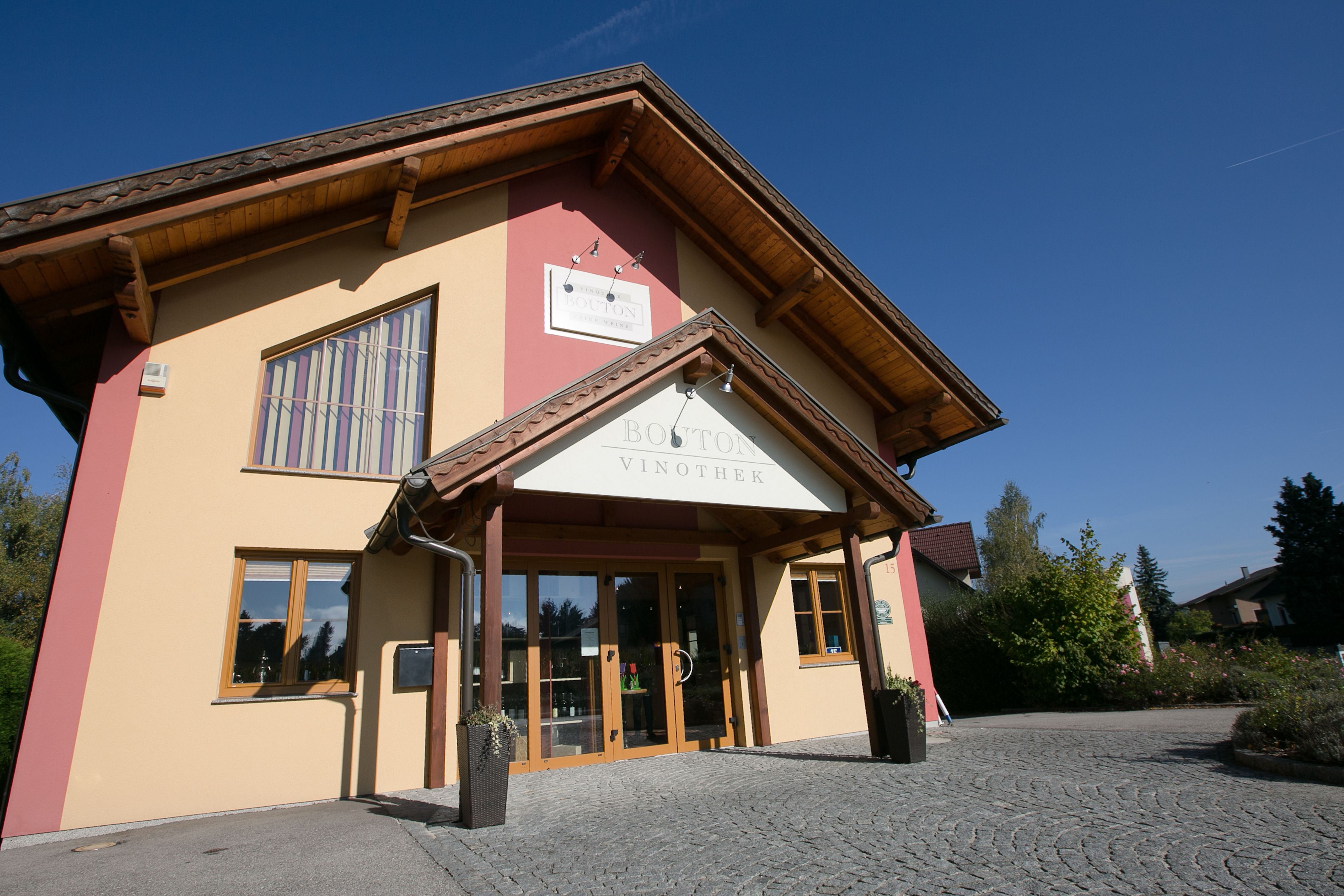 Entrance to the Bouton wine shop with yellow façade and wooden roof.