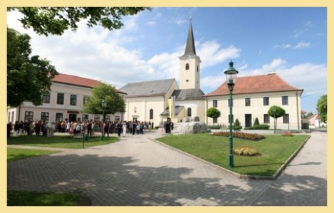 Absdorf parish church with surrounding square and gathering of people.