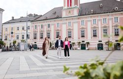 Three people in business outfits in front of the baroque town hall of St. Poelten