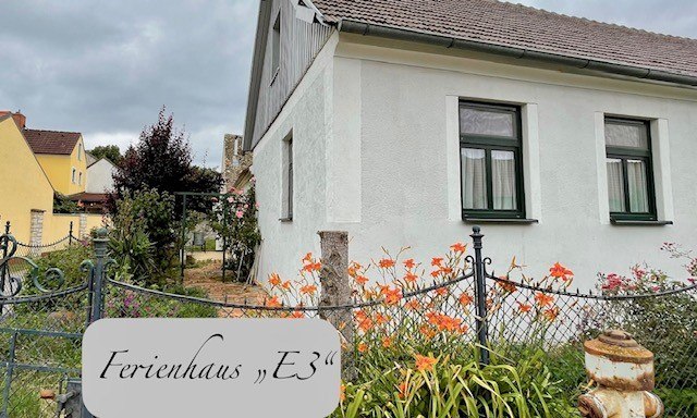 Exterior view of a white vacation home with garden and flowers.