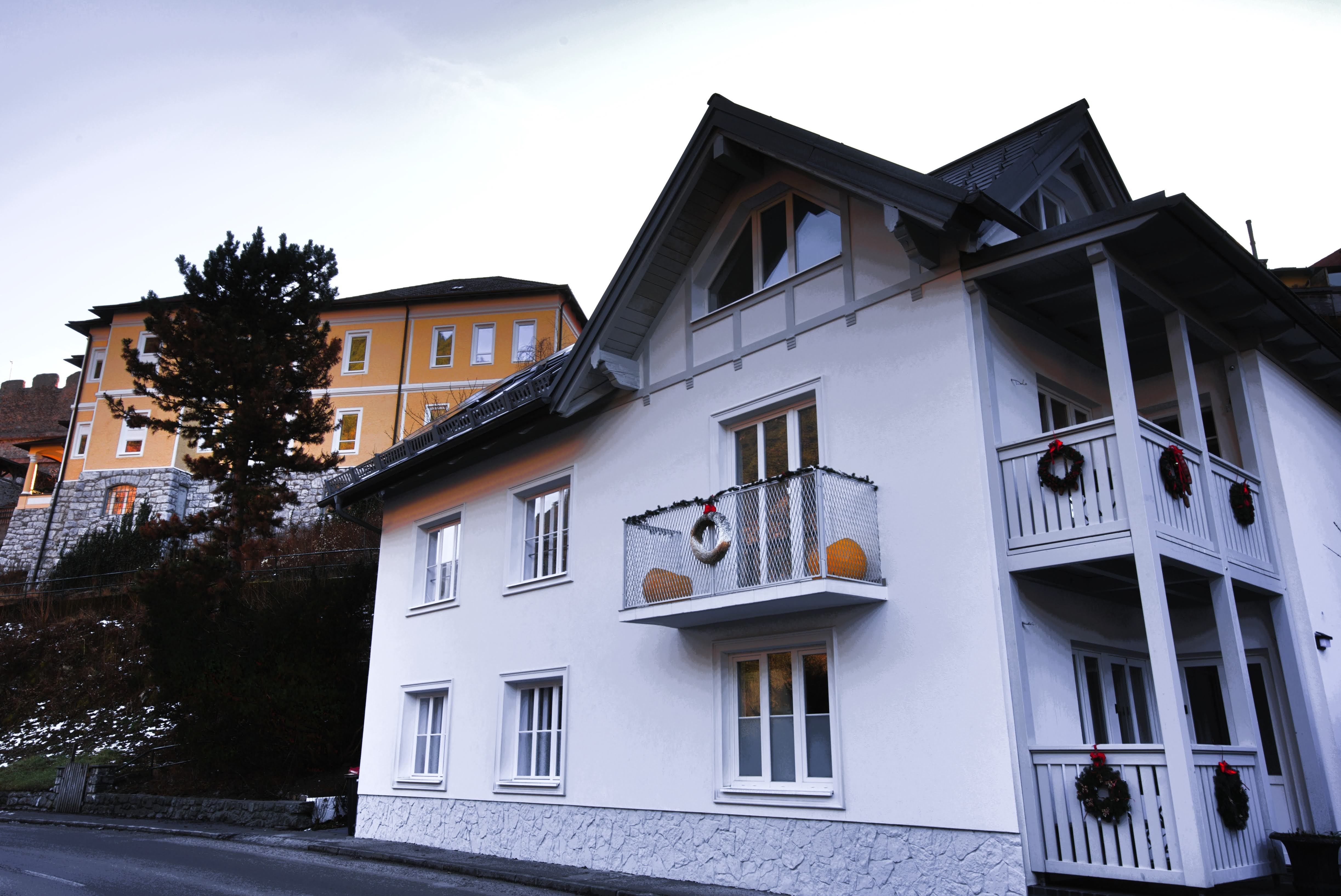 Two houses, one white with a balcony, the other yellow, with decoration.