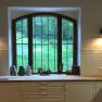 Kitchen with large window, wooden worktop and white cupboards.