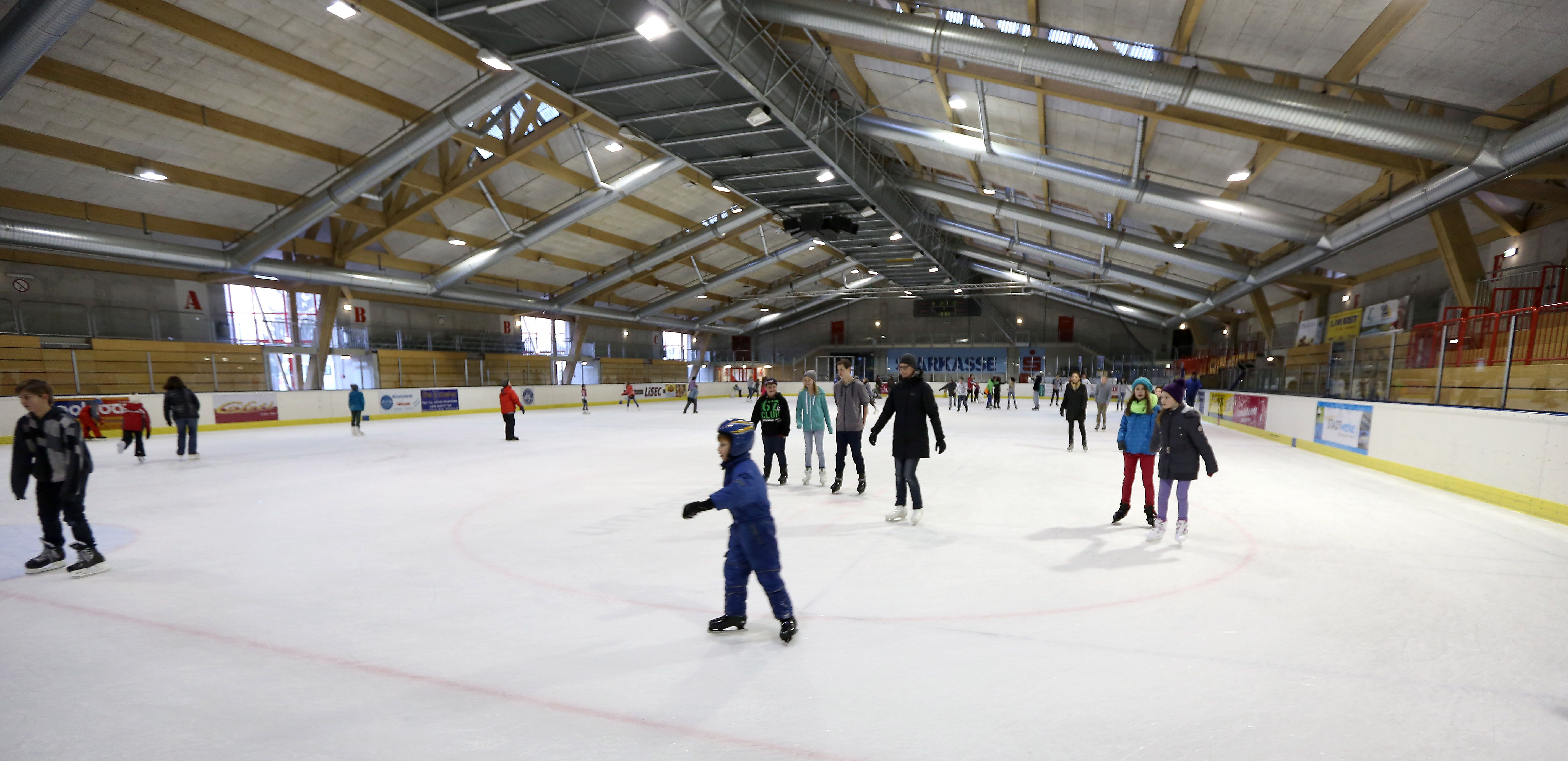 People ice skating in a large ice rink.