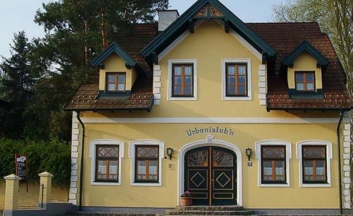Yellow building with the inscription 'Urbanistubn', surrounded by trees.