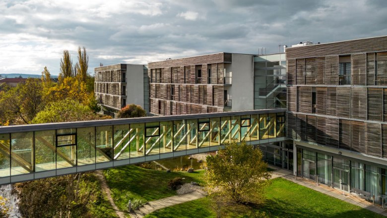 Glass-roofed transition between Therme Laa and hotel building, surrounded by green landscape.
