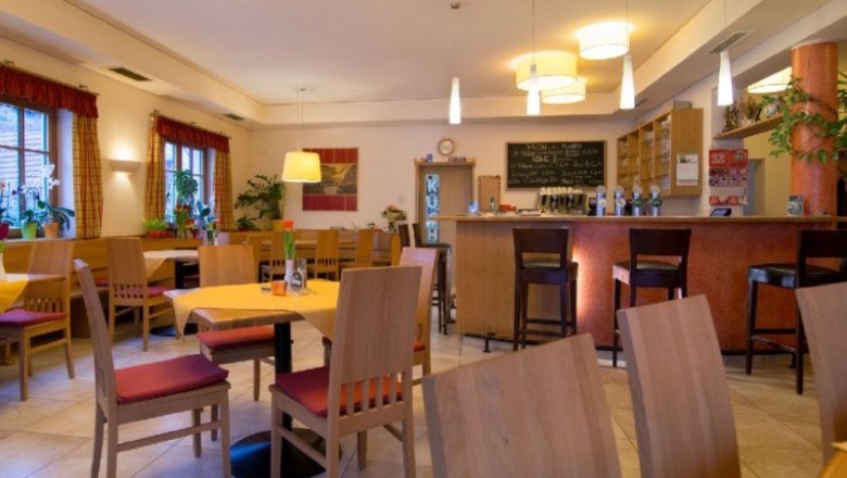Interior view of a cozy restaurant with wooden furniture and bar.